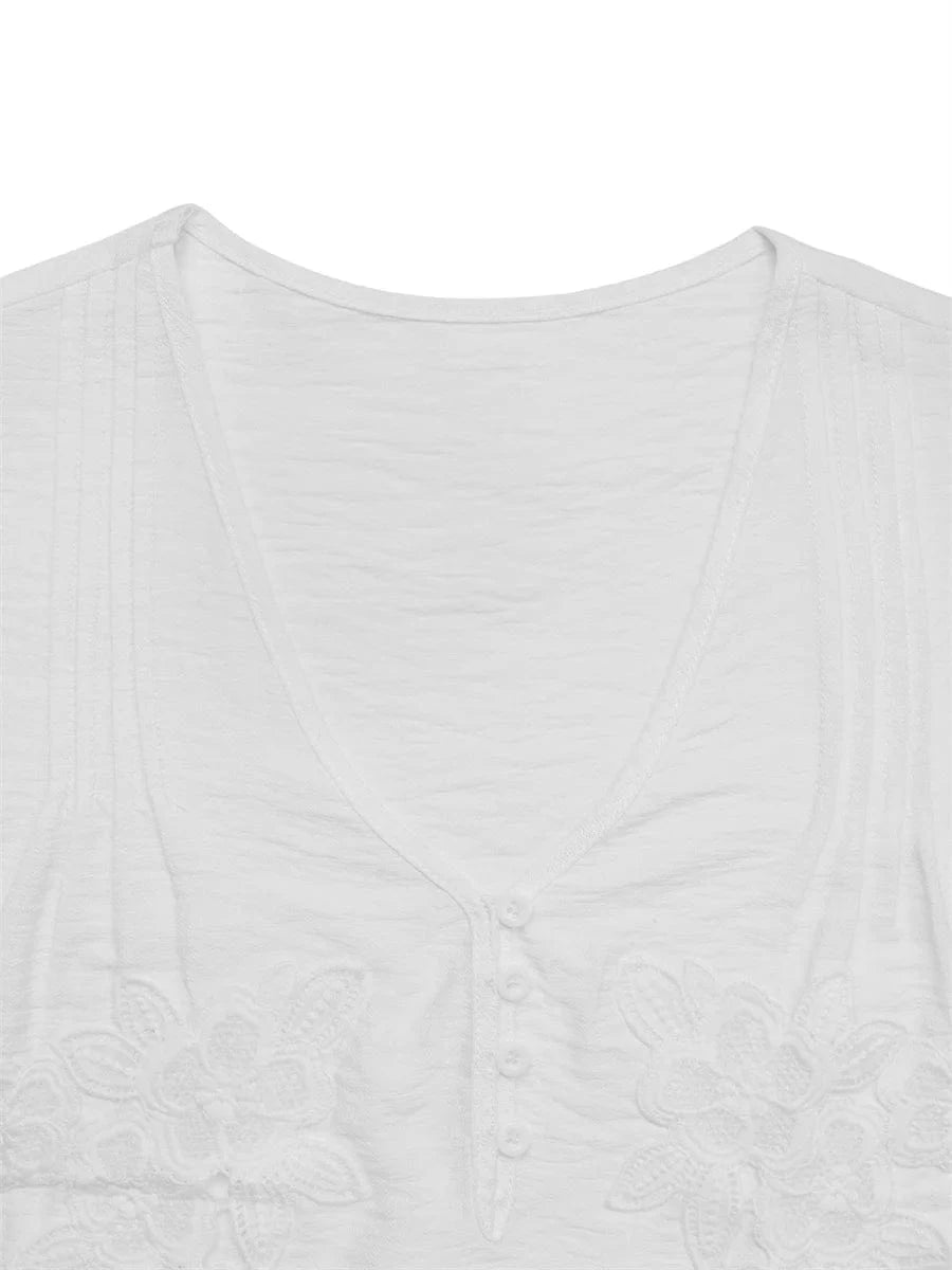 Vit crêppad blus med blommiga applikationer